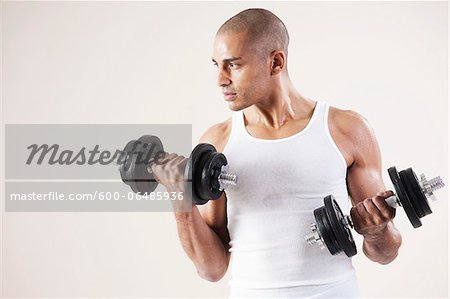 Man Wearing Work Out Clothes and Lifting Weights in Studio with White Background