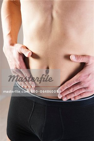 Close-up of Young Man in Boxer Briefs Touching Stomach in Studio