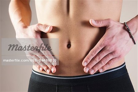 https://image1.masterfile.com/getImage/600-06486010em-closeup-of-young-man-in-underwear-touching-stomach-in-studio-stock.jpg