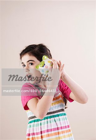 Portrait of Girl Shaking Piggy Bank and Listening in Studio