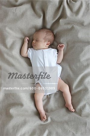 newborn baby girl in a white undershirt sleeping on a bed, Ontario, Canada
