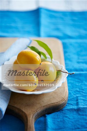 four whole meyer lemons in a bowl with lemon leaves on a cutting board, Canada
