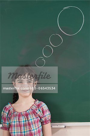 Girl in Front of Chalkboard with Thought Bubble in Classroom