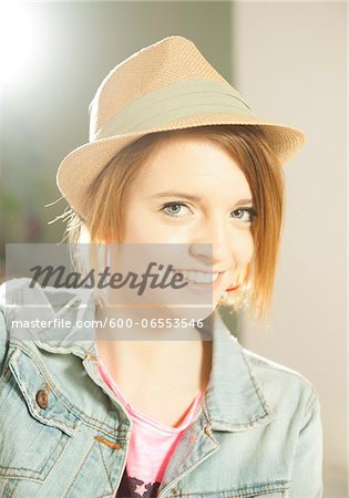 Head and shoulders portrait of teenage girl wearing hat in studio.