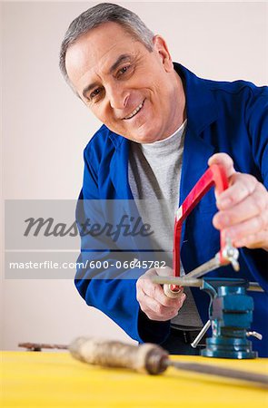 Man Cutting a Pipe for a Plumbing Project, in Studio
