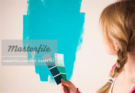 Studio Shot of Young Woman Holding Colour Swatches, Deciding Between Paint Colours Studio Shot of Young Woman Holding Colour Swatches, Deciding Between Paint Colours