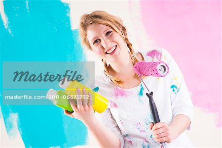 Studio Shot of Young Woman Holding Paint Roller, Deciding Between Paint Colours