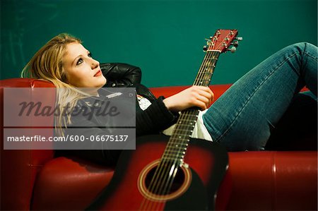Woman Lying on Sofa and Holding Acoustic Guitar Woman Lying on Sofa and Holding Acoustic Guitar