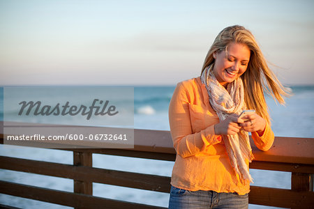 Young Woman Standing on Pier at Beach, Texting on Cell Phone, Jupiter, Palm Beach County, Florida, USA