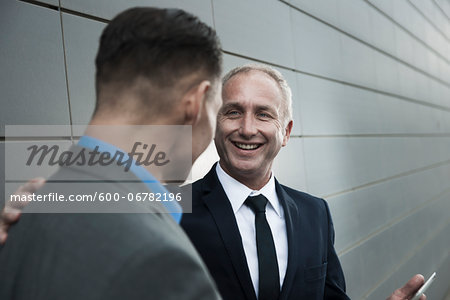 Mature businessmen standing in front of wall, talking