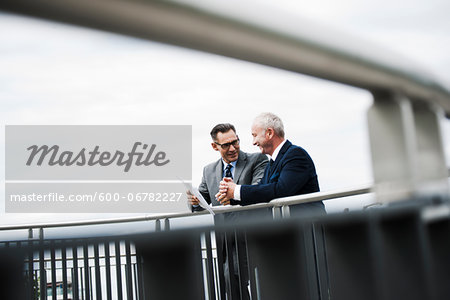 Mature businessmen standing on bridge talking, Mannheim, Germany