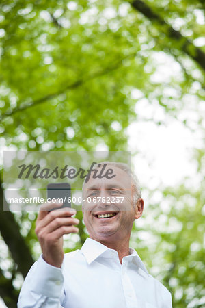 Close-up of mature man looking at smartphone in park, Mannheim, Germany