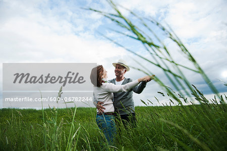Mature couple dancing in field of grass, Germany