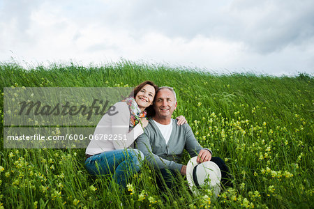 Portrait of mature couple sitting in field of grass, embracing, Germany Portrait of mature couple sitting in field of grass, embracing, Germany