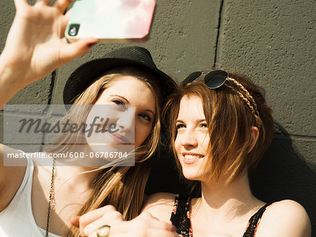 Close-up of young women taking photo of themselves with smart phone