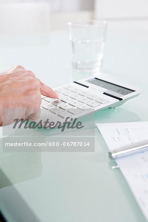 Close-up of Mature Woman's Hand using Calculator in Office