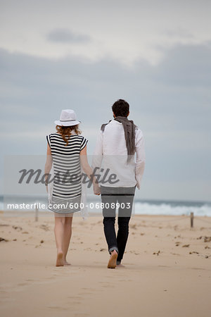 Back View of Couple Walking and Holding Hands on Beach, Sardinia, Italy Back View of Couple Walking and Holding Hands on Beach, Sardinia, Italy