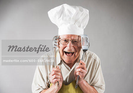 Senior Man with Cooking Utensils wearing Apron and Chef's Hat, Studio Shot