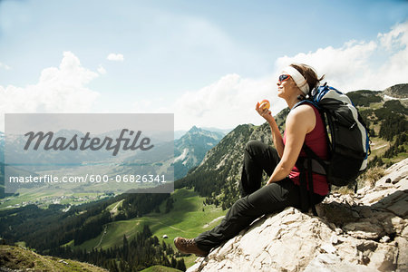 Mature woman sitting on cliff, hiking in mountains, Tannheim Valley, Austria Mature woman sitting on cliff, hiking in mountains, Tannheim Valley, Austria