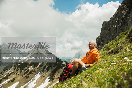 Mature man sitting on grass, hiking in mountains, Tannheim Valley, Austria