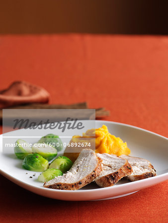 Sliced Turkey Breast with Brussels Sprouts and Mashed Sweet Potatoes for Thanksgiving Dinner on Red Background