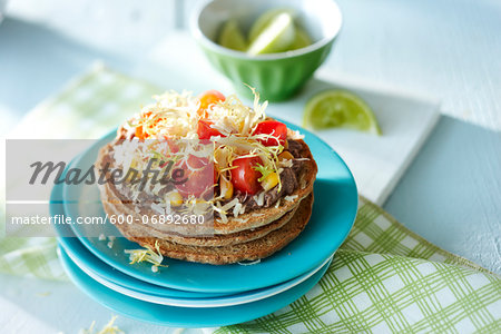 Open Faced Vegetarian Sandwich with Black Beans, Tomatoes, Lettuce, and Corn, with Lime Wedges in the Background