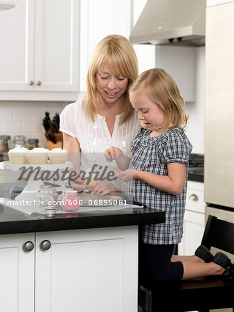 Mother and Daughter Decorating Cupcakes in open concept Kitchen, Toronto, Ontario, Canada Mother and Daughter Decorating Cupcakes in open concept Kitchen, Toronto, Ontario, Canada