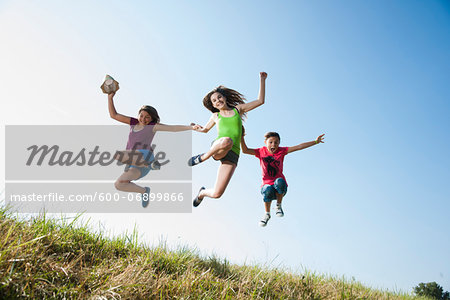 Girls jumping in mid-air over field, Germany Girls jumping in mid-air over field, Germany
