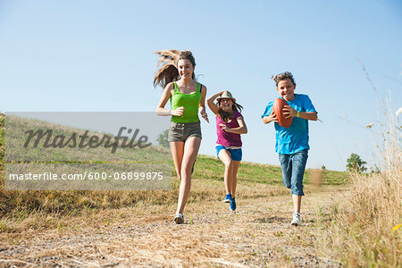 Girls running along pathway in field, Germany