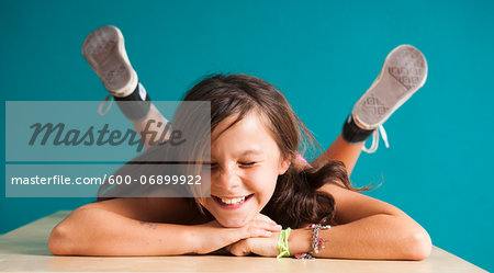 Girl lying on floor with eyes closed, making funny faces, Germany
