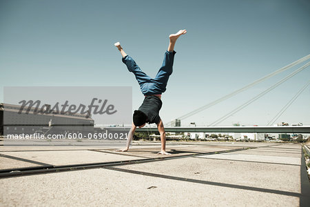 Teenaged boy doing handstand on cement road, freerunning, Germany
