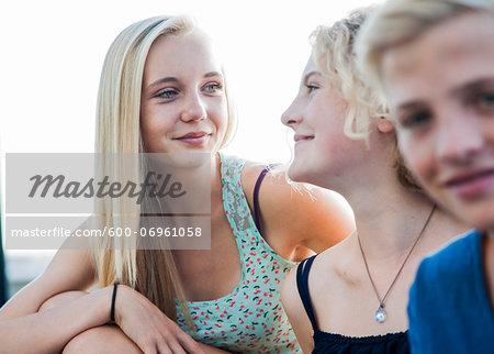 Close-up portrait of teenage girls and boy sitting outdoors, Germany