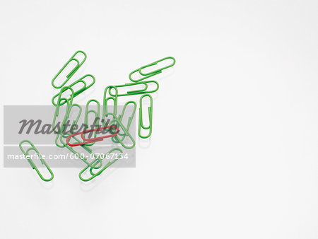 Green and red paper clips on white background, studio shot