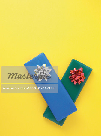 Gifts wrapped in colorful paper on yellow background, studio shot