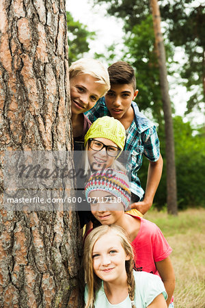 Portrait of group of children posing next to tree in park, Germany