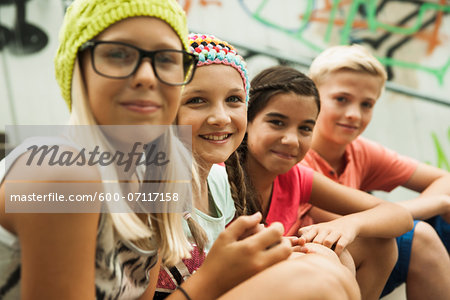 Close-up of group of children sitting on stairs outdoors, looking at camera, Germany