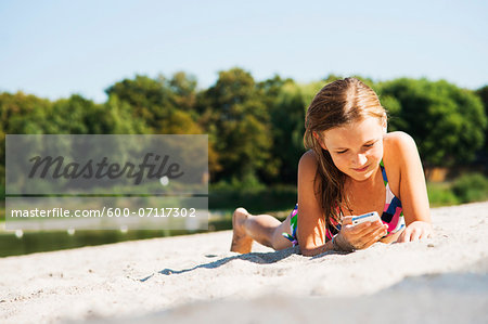Girl using Cell Phone at Beach, Lampertheim, Hesse, Germany