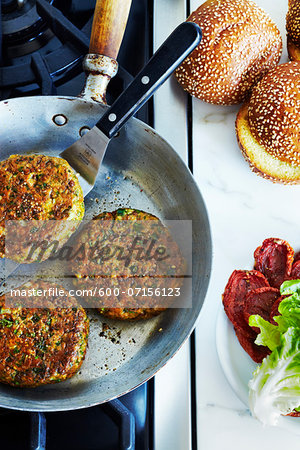 Chickpea falafel burgers in frying pan on stove, studio shot Chickpea falafel burgers in frying pan on stove, studio shot