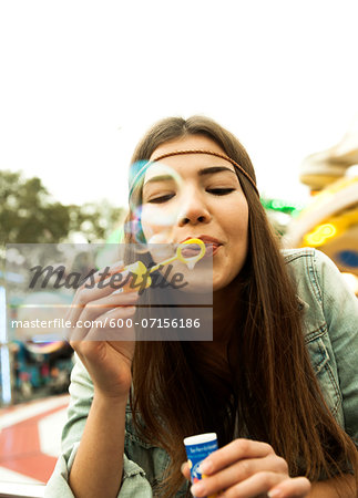 Close-up portrait of teenage girl blowing bubbles at amusement park, Germany