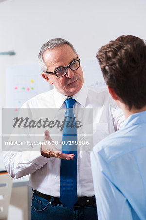 Businessman explaining work to apprentice in office, Germany