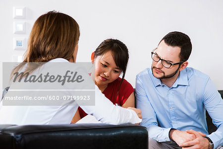 Backview of businesswoman in discussion with young couple, Germany