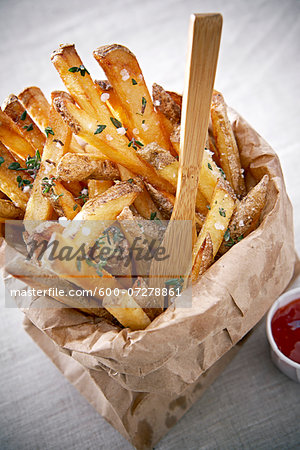 Seasoned French Fries in Paper Bag with Wooden Fork and Ketchup
