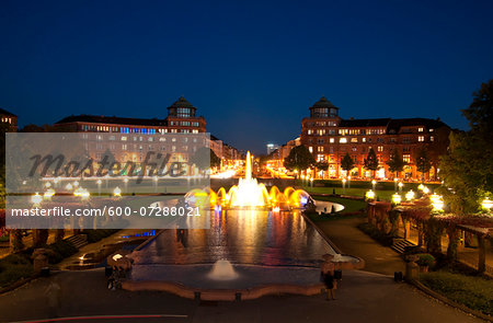 View of Water Fountain at night, with Arcade Buildings in background at Freidrichsplatz, Mannheim, Germany