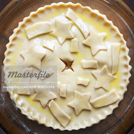 Overhead view of unbaked apple pie with star shaped cut-outs on top, studio shot