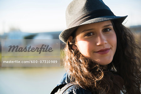 Close-up portrait of teenage girl outdoors, wearing fedora, smiling and looking at camera, Germany