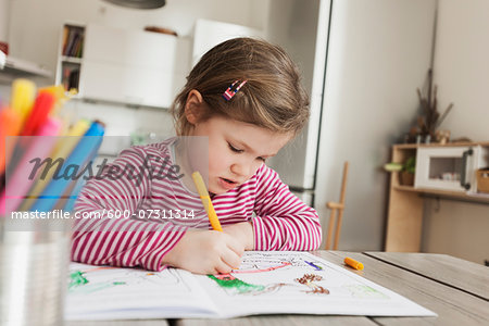 Girl Sitting at Table and Colouring Pictures