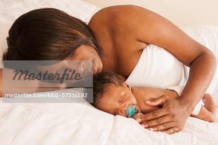 Mother laying with Sleeping Newborn Baby