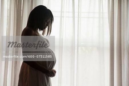 Silhouette of Pregnant Woman Standing by Window