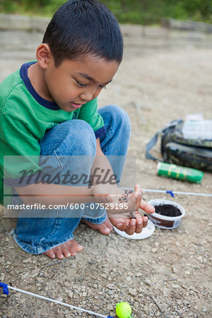 Crouching Boy Preparing Worm for Fishing, Lake Fairfax, Reston, Virginia, USA