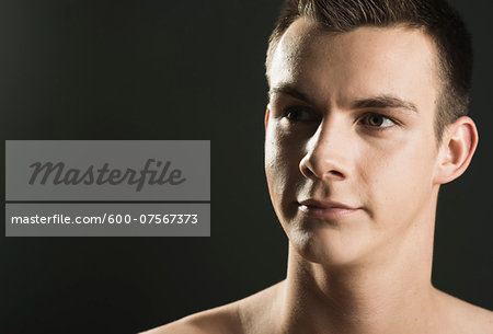 Close-up portrait of young man, looking to th side, studio shot on black background